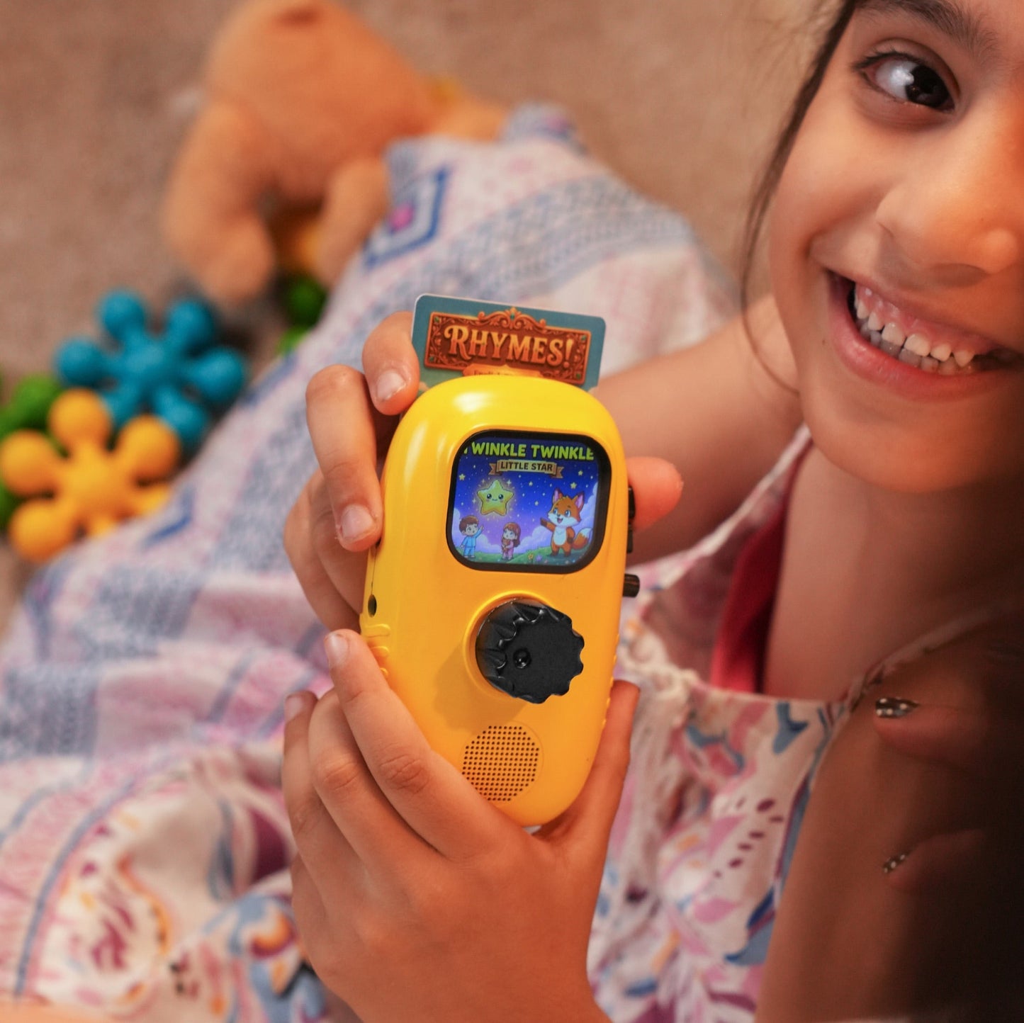 A girl holding Cheeko with a Rhymes card playing Twinkle Twinkle Little Star at bedtime