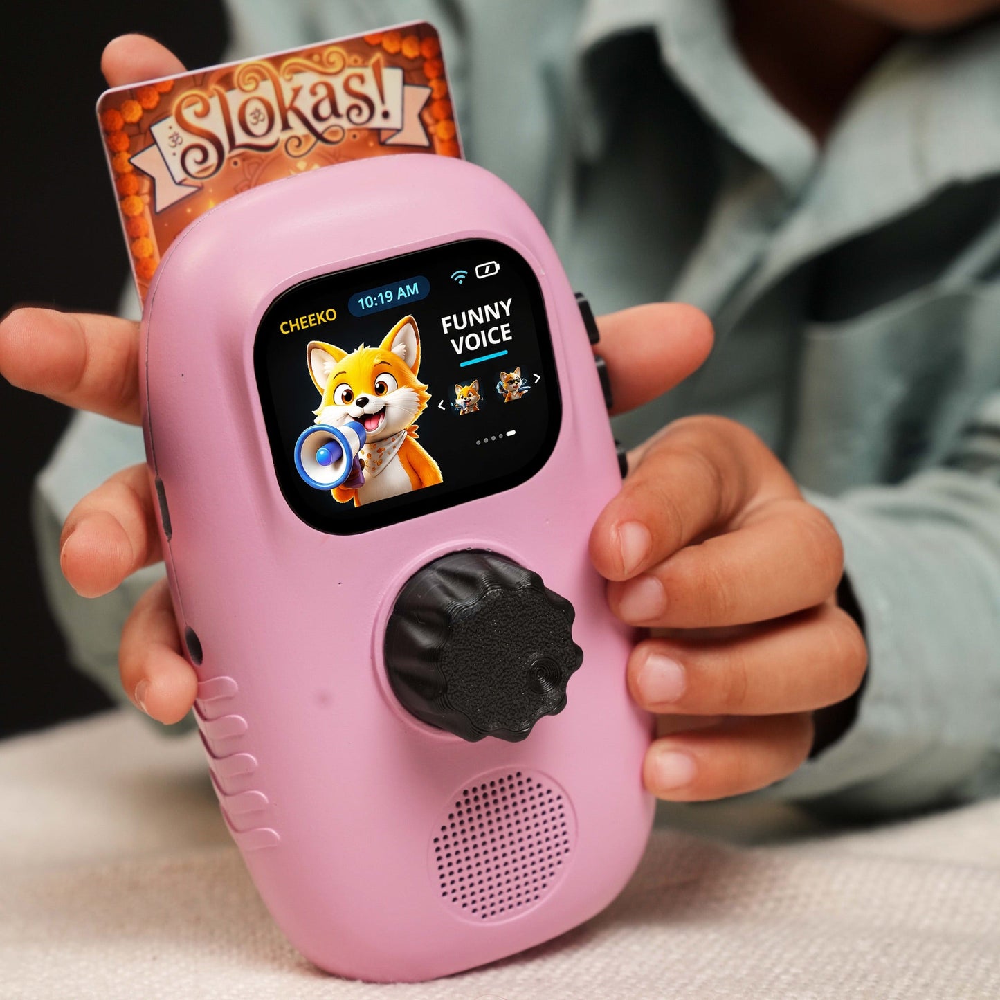 A pink Cheeko held in a child's hands with a Slokas story card inserted